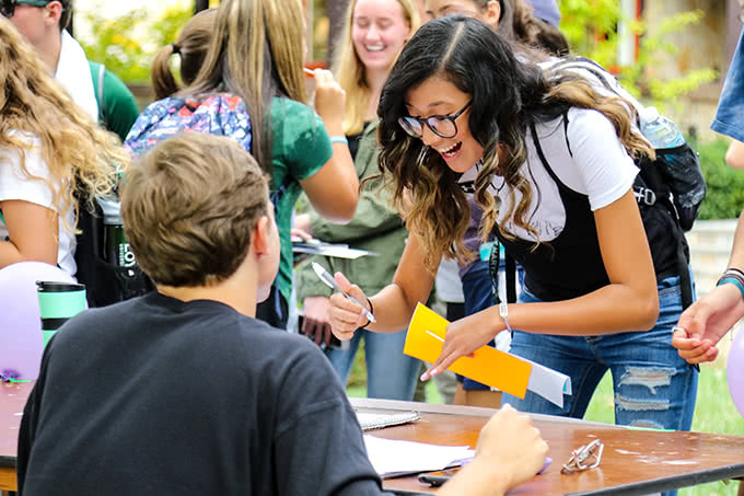 Student smiling at Activities Fair signing a form