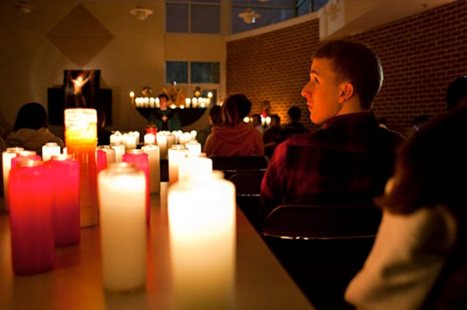Student looking at candles in darkened room with altar at front