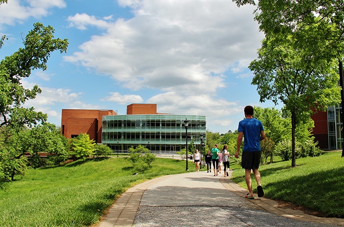 Students walk down a pedestrian path towards the Loyola Notre Dame Library