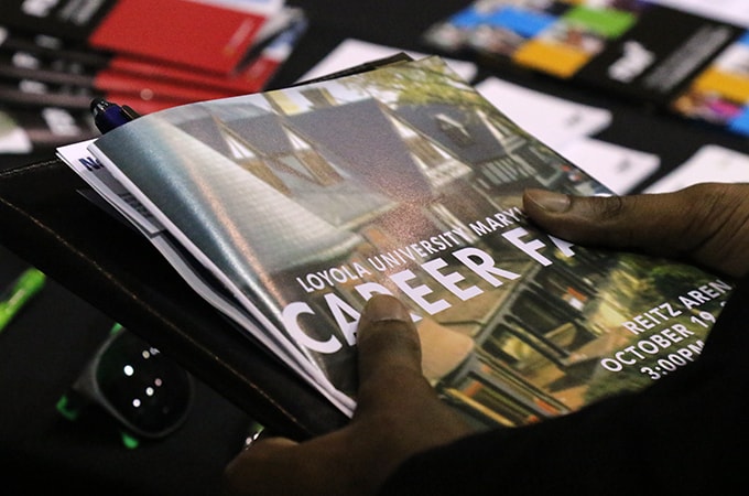 A student holding print collateral from one of Loyola's career fairs