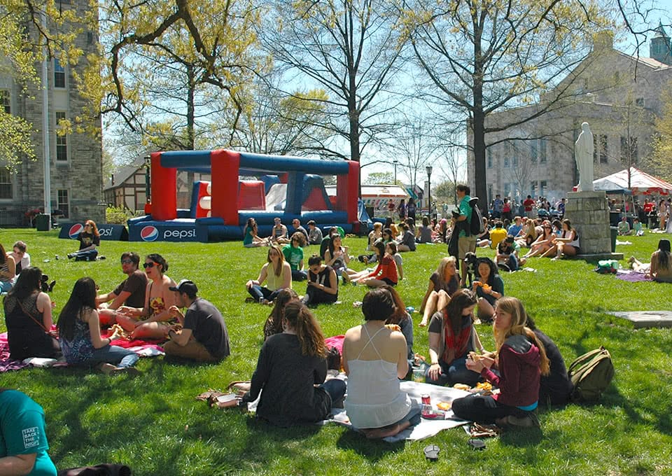Students sitting in the grass eating while listening to music
