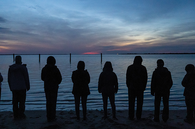 Students look out to sea after the sunset.