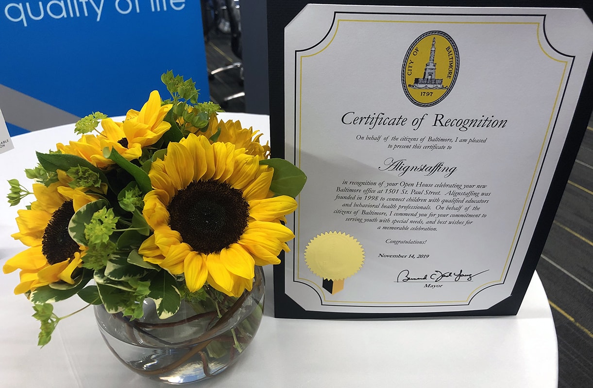 Photo of Certificate of Recognition from the City of Baltimore and a vase of sunflowers sitting on a table
