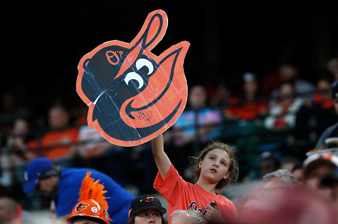 A young girl holds up an Orioles sign in the crowd during a baseball game