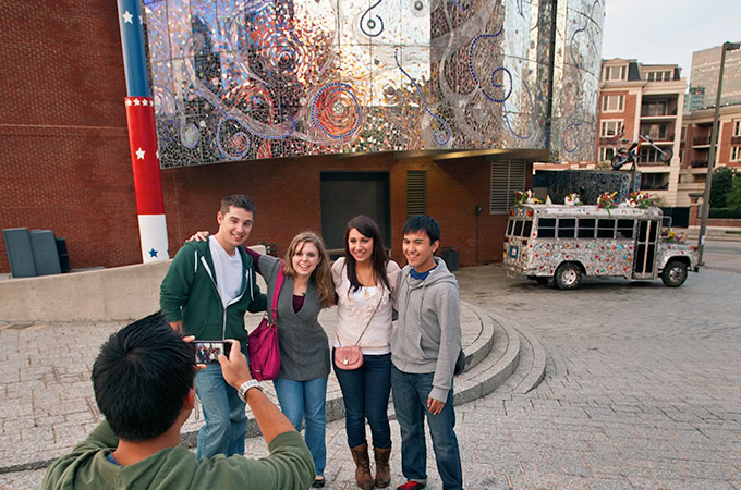 Students posing for a picture in front of the metallic and tile facade of The American Visionary Arts Museum