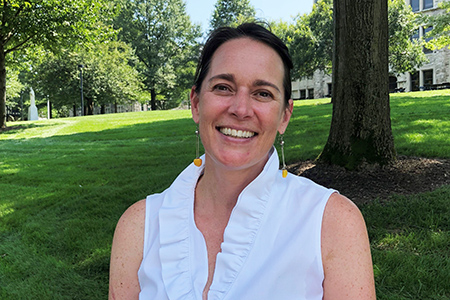 Wendy smiles with Loyola's sunny quad behind her.