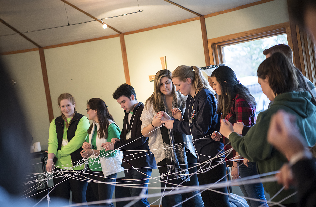 Students hold a web of strings.