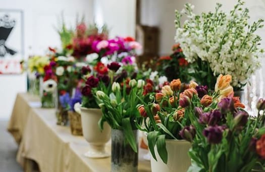 A large group of flowers in vases displayed on a table