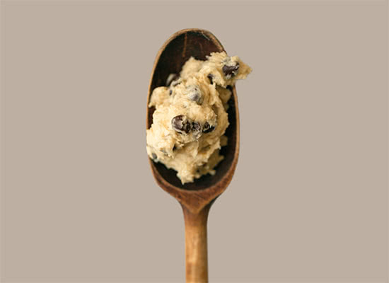 Close up photo of a scoop of chocolate chip cookie dough on a wooden spoon