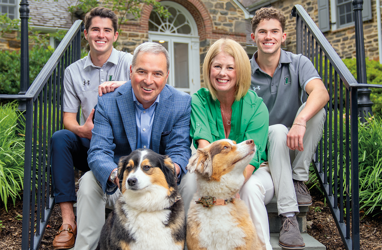 The Sawyer family pose for a photo with their two dogs sitting on the stairs outside their home