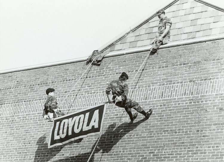 ROTC cadets rappelling down the side of the building with a Loyola banner