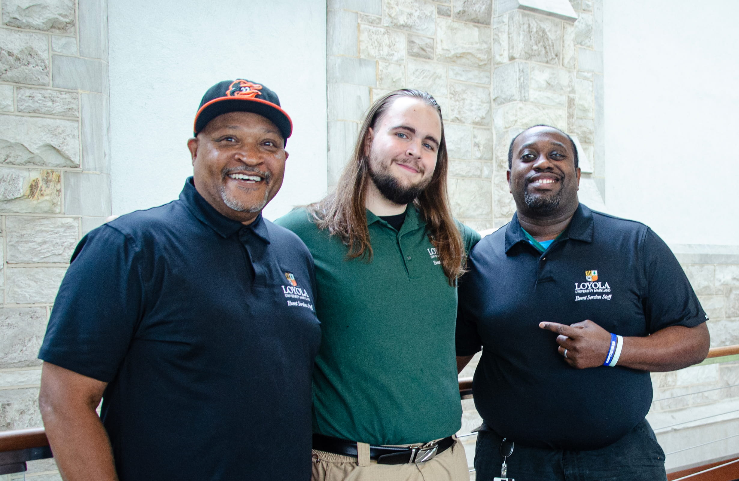 Three men pose together, smiling