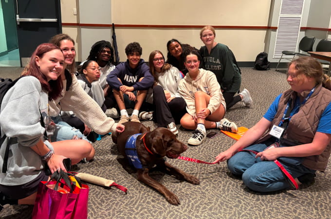 A group of students at Wellfest sitting with a therapy dog