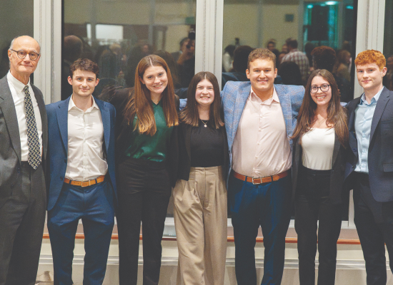A group of 6 students and their professors in business attire.