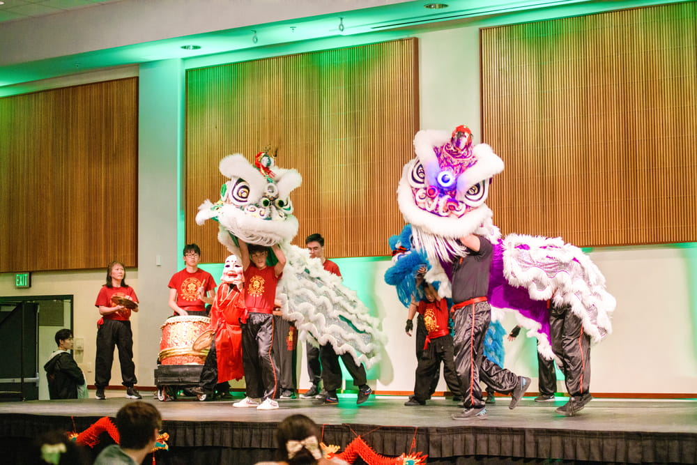 Performers in colorful lion costumes dance on stage during Loyola’s AsiaFest celebration