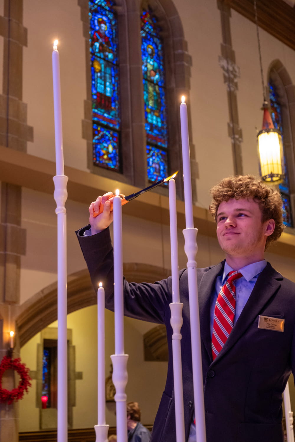 A student using a lighter to light candles in Alumni Memorial Chapel.