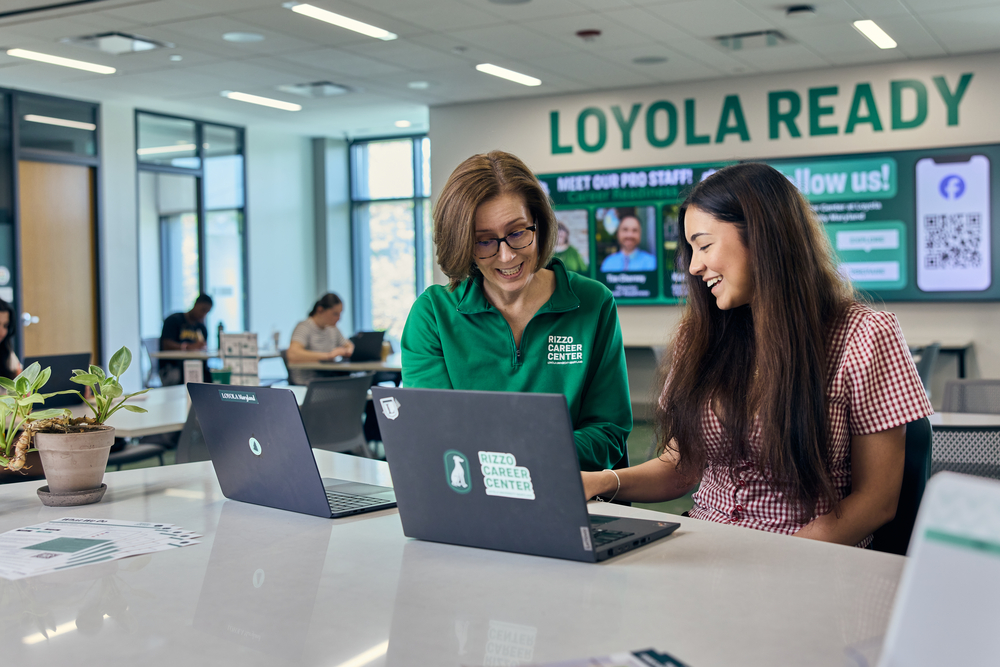 A Rizzo Career Center staff member and a student chatting and looking at their laptops.