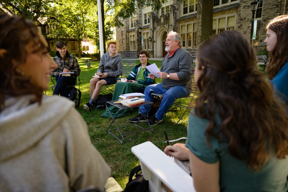 A professor and a group of students having a class discussion on the Quad