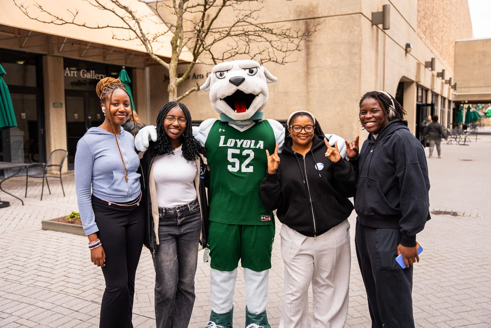 Iggy the Greyhound poses with a group of students in front of the DeChiaro College Center.