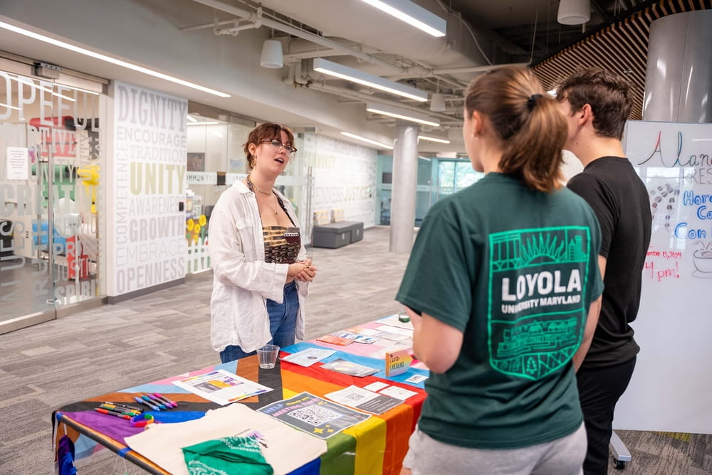 Students gather at a table promoting the Spectrum Experience, an organization supporting LGBTQ+ students through advocacy, community, education, and activism