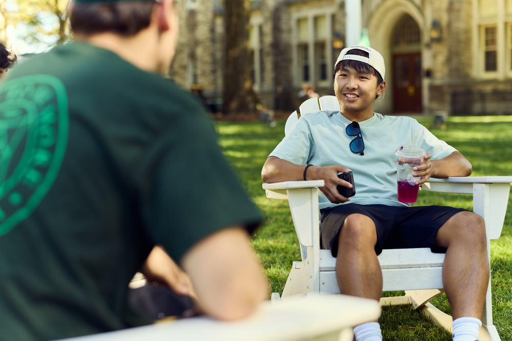Two students sitting in Adirondack chairs on the Quad.