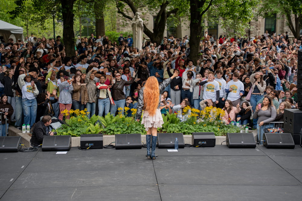 A large crowd gathered in front of a stage watching a live music performance
