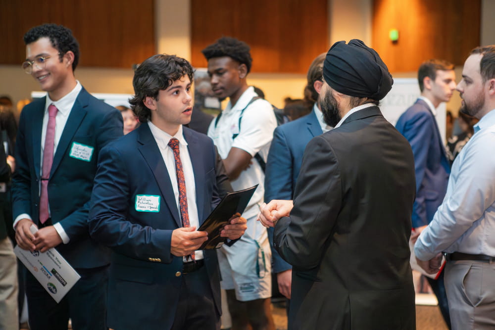A student wearing a business suit talking to a recruiter at the career fair