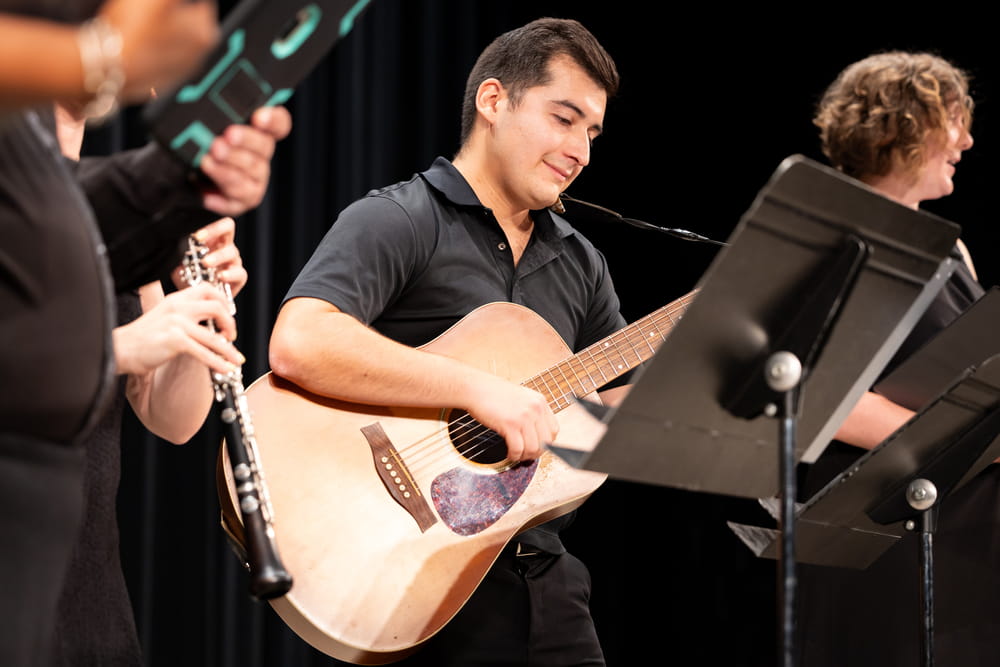 A student playing a guitar during a concert