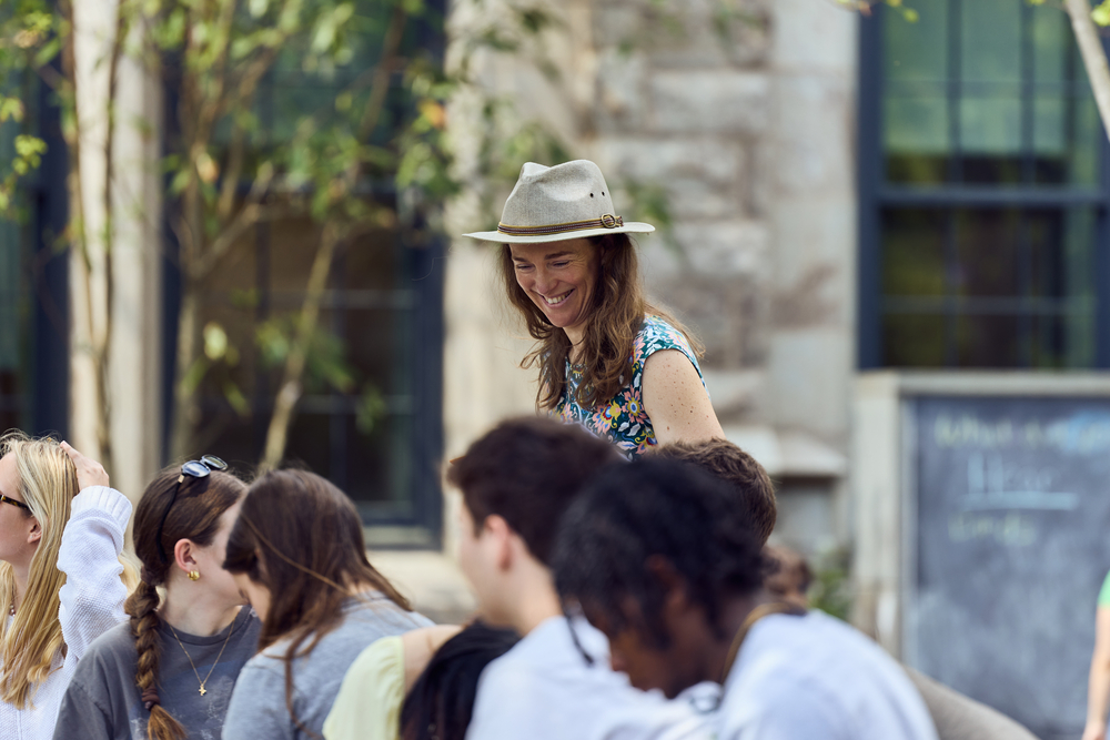 A professor chats with her students outside.