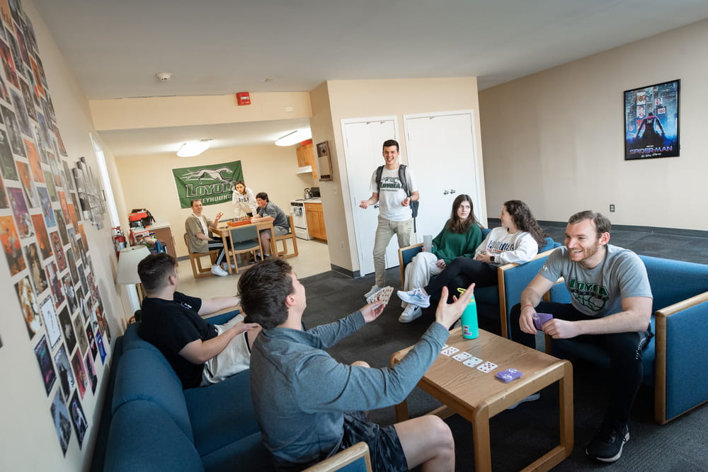 Students smiling and laughing around relaxing and playing games around a table in a living room