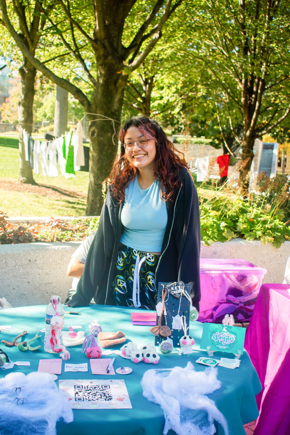 A student standing behind a table displaying her artwork for sale