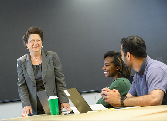 Sellinger professor works with grad students in a classroom
