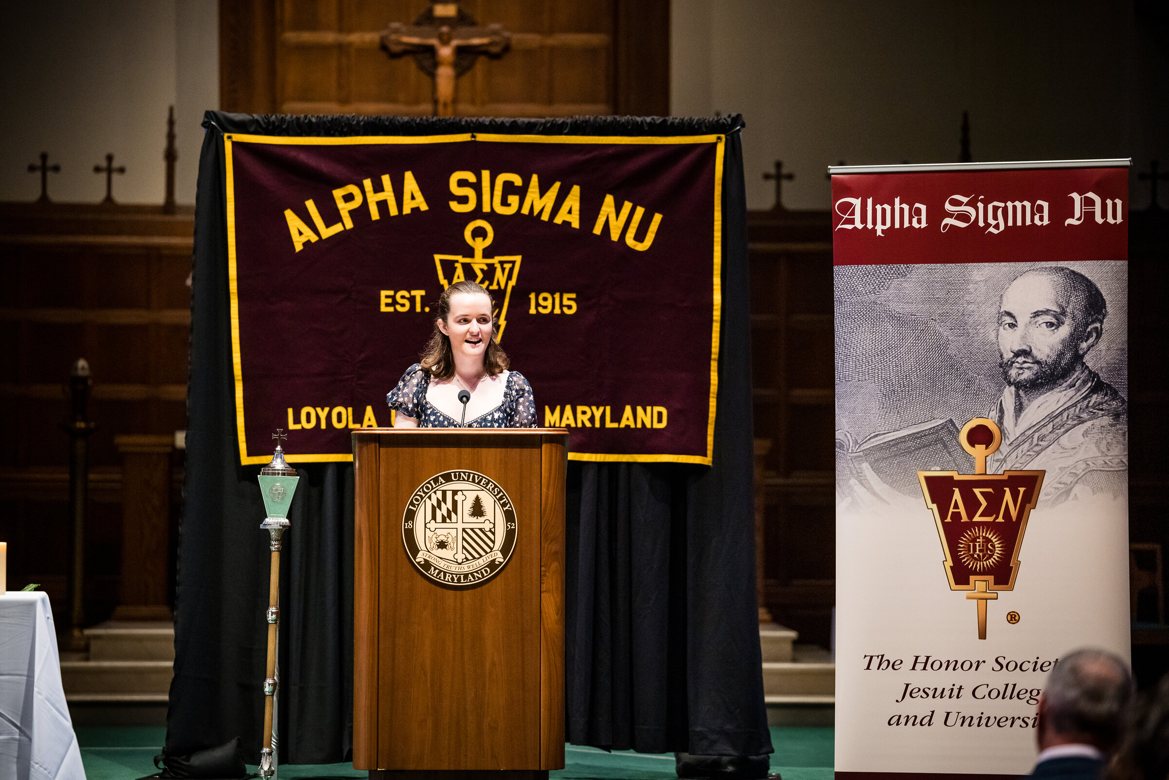 Alpha Sigma Nu member speaking at a podium 