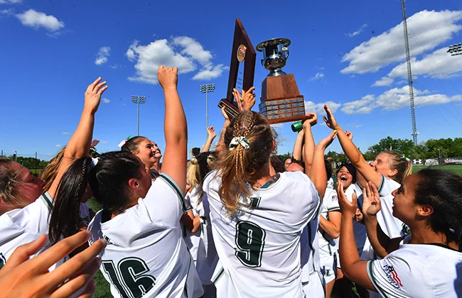 The Loyola Women's Lacrosse team holds up trophies after winning the championship game