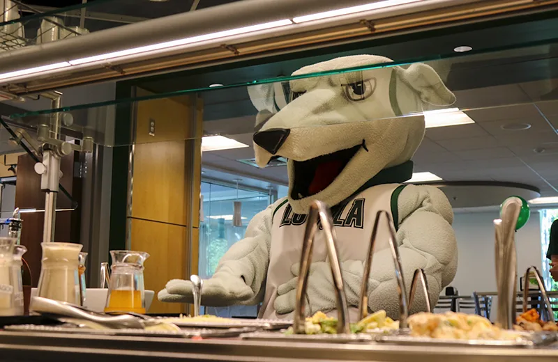 The Greyhound mascot in front of a salad bar