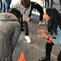 Three students gathered around a traffic cone in a thinking activity
