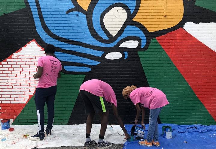 Three young people paint a mural