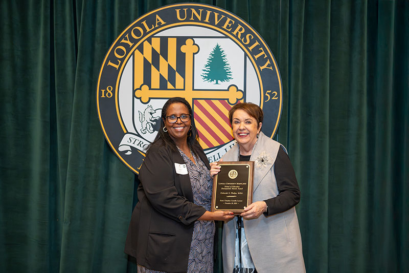 Debbie Phelps, M.Ed. '98, receives the inaugural School of Education Distinguished Alumni Award from Afra Ahmed Hersi, Ph.D., dean of the School of Education.