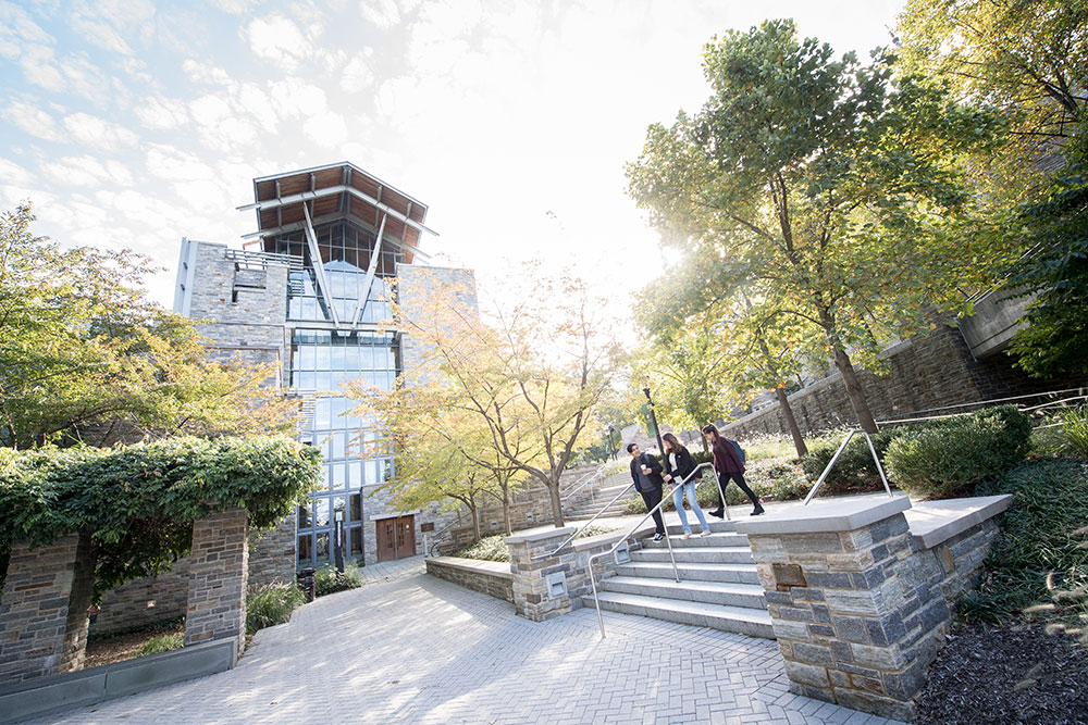 Three students walking in front of the Sellinger School of Business and Management