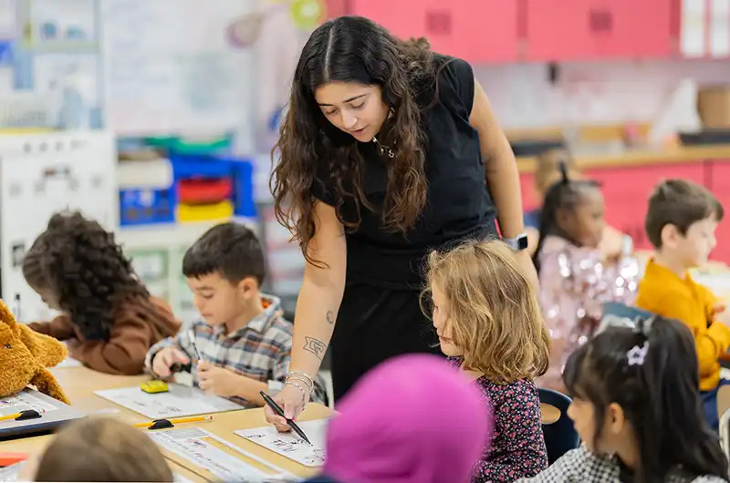 Teacher walks through elementary classroom assisting students