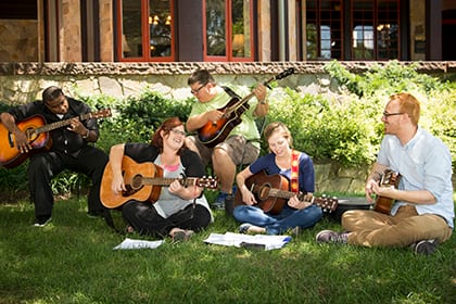 Kodaly instructors and students playing guitar outside on Loyola's academic Quad