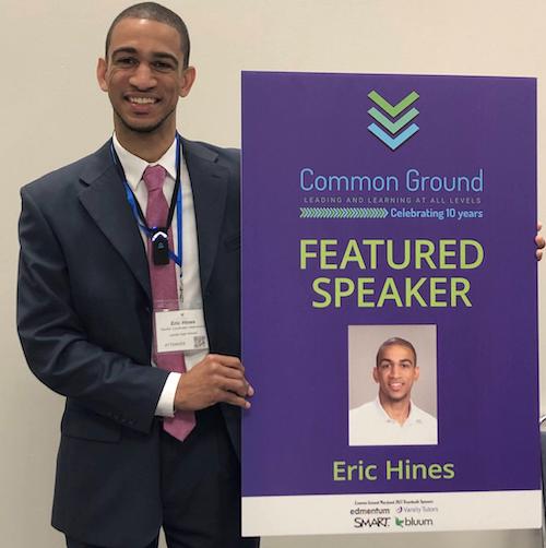 Man in suit standing holding poster with the words  'Featured Speaker' and a picture of himself
