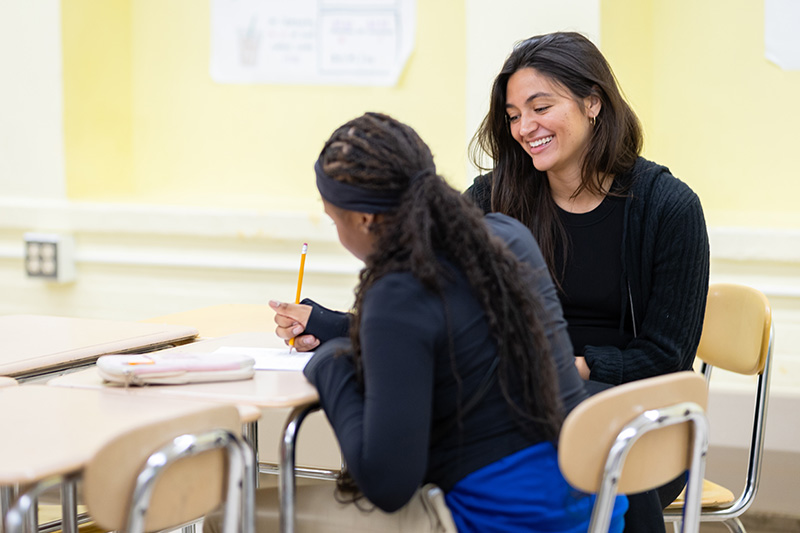 Teacher looking over the shoulder of student working at desk.