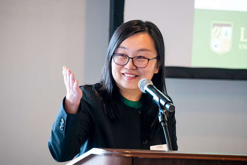 Qi Shi, Ph.D., LCPC, Director of the Center for Research and Evaluation speaks at a podium.