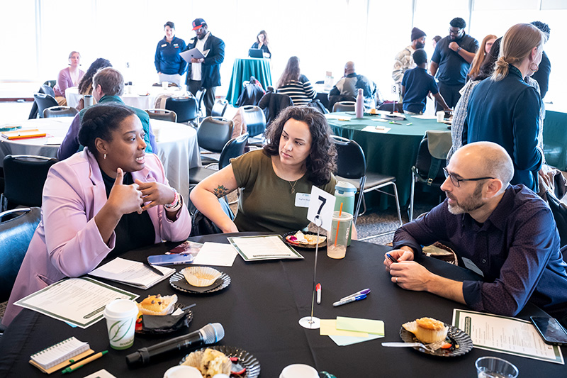Group talks while sittig at a table at the 2026 CRE Annual Symposium.