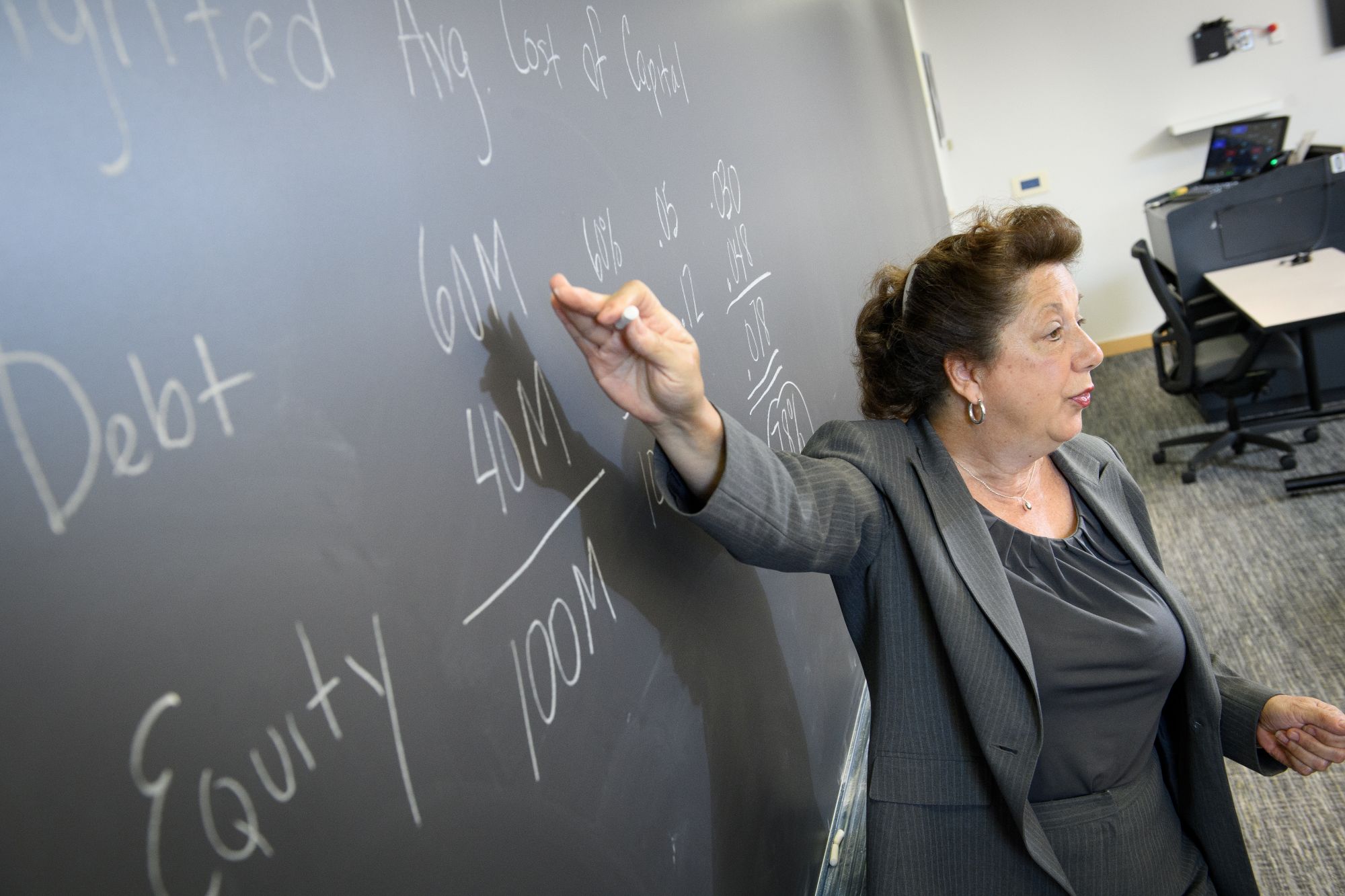 a woman points at math problems on a chalkboard