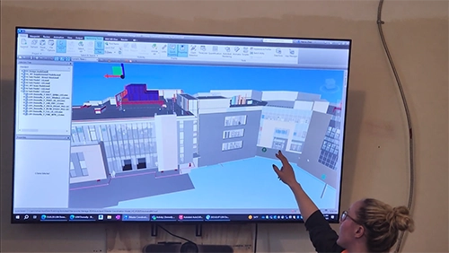 Person points at screen rendering of building