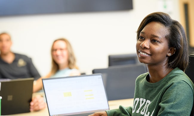 A student smiles as she listens to a professor's seminar